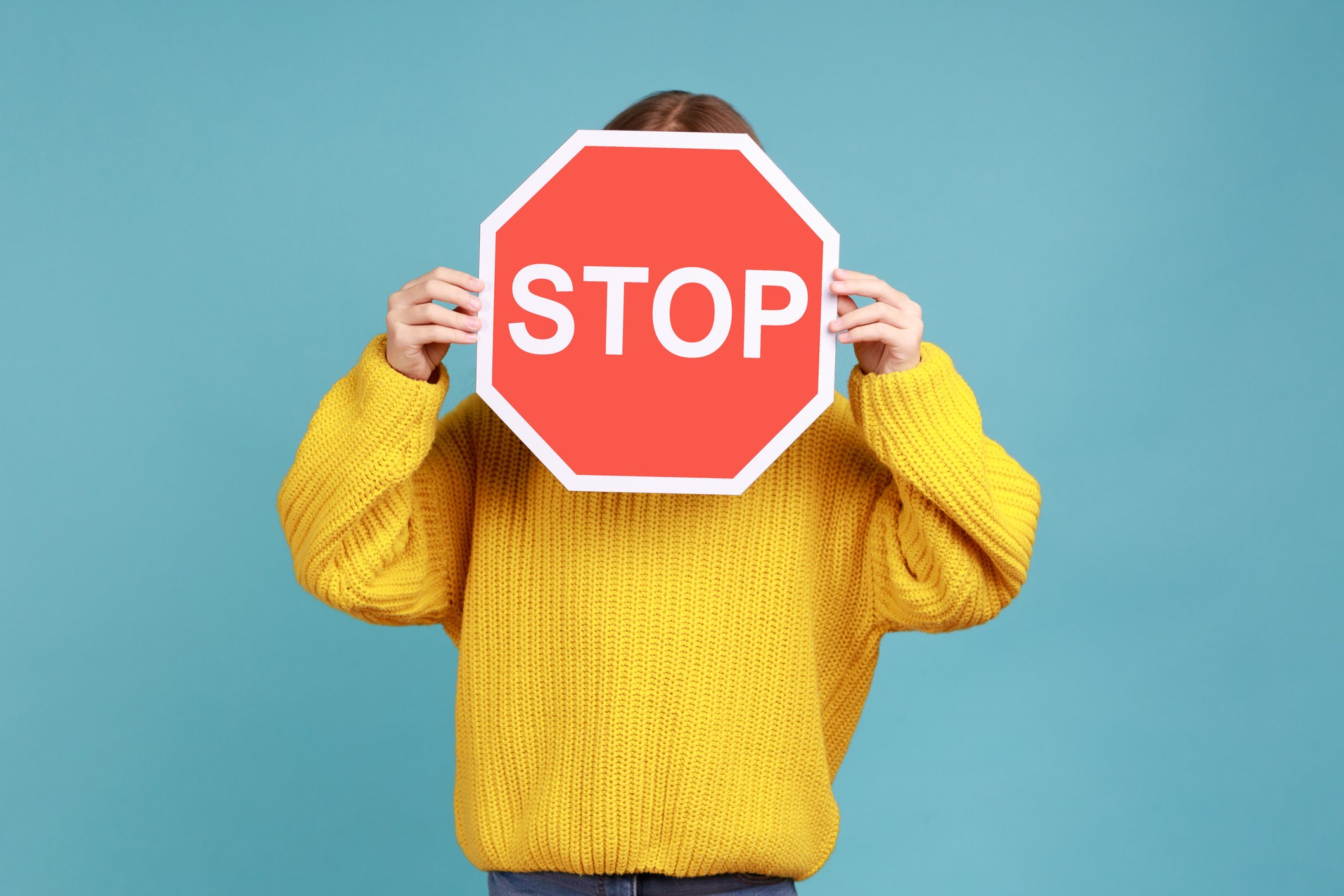A person holding a stop sign in front of their face