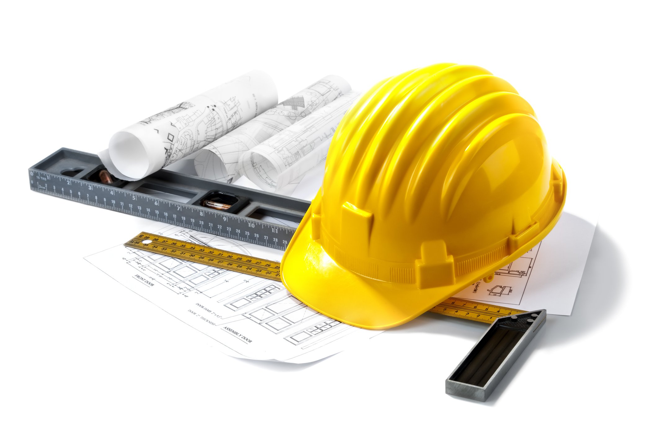 A yellow hard hat resting on architectural blueprints with tools nearby