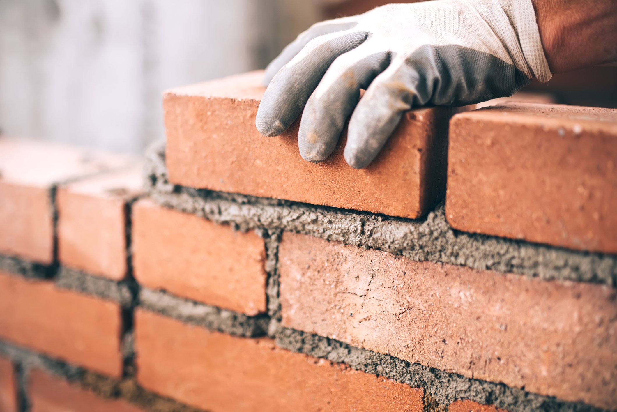 A construction worker laying bricks on a new wall