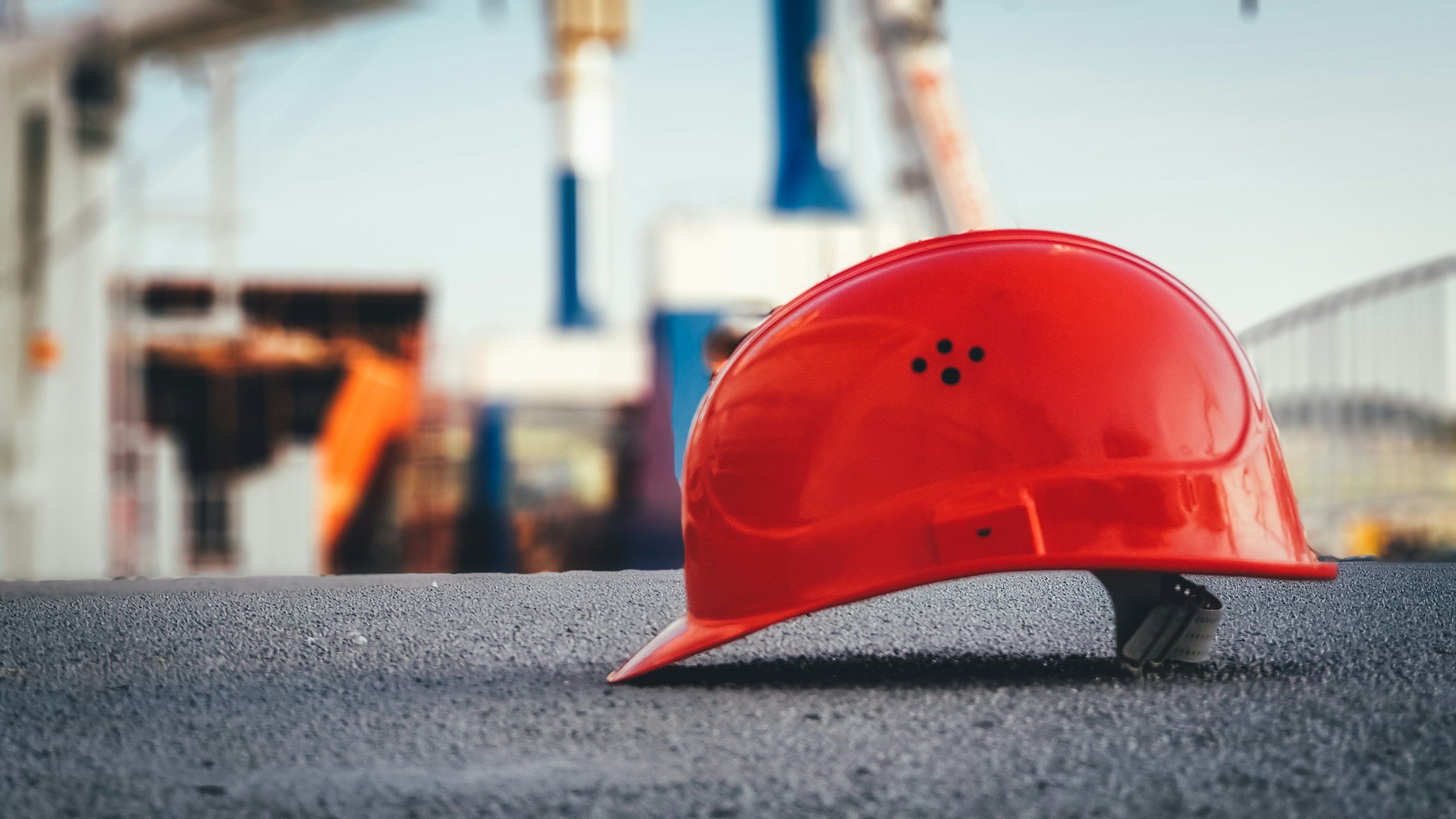 A person reviewing planning documents and a hard hat