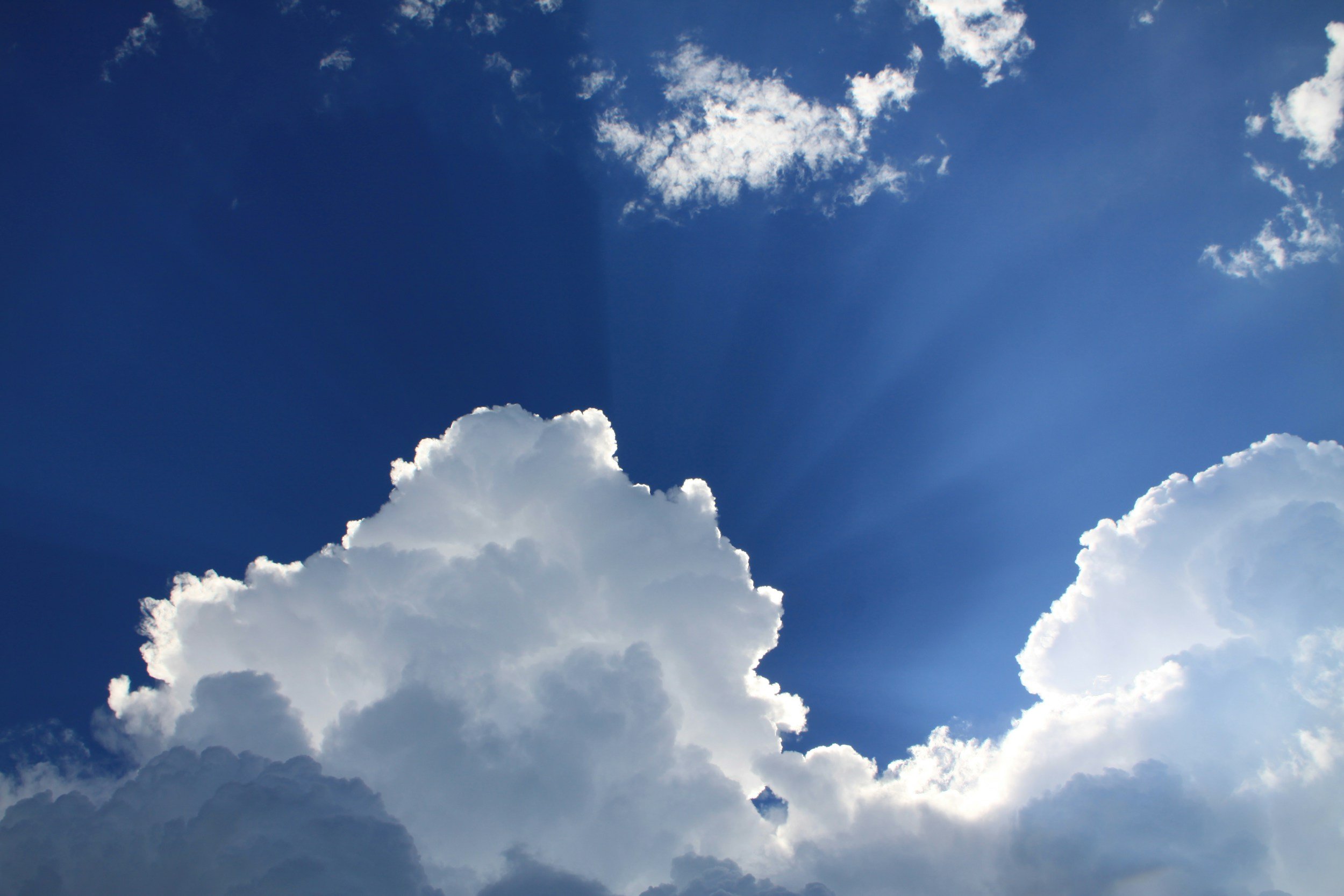 Bright blue sky with white fluffy clouds and sun rays