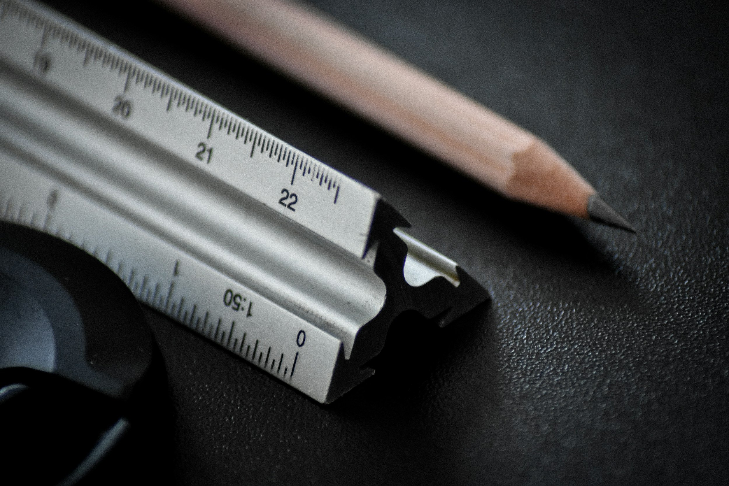 Architectural scale ruler and pencil on a dark surface