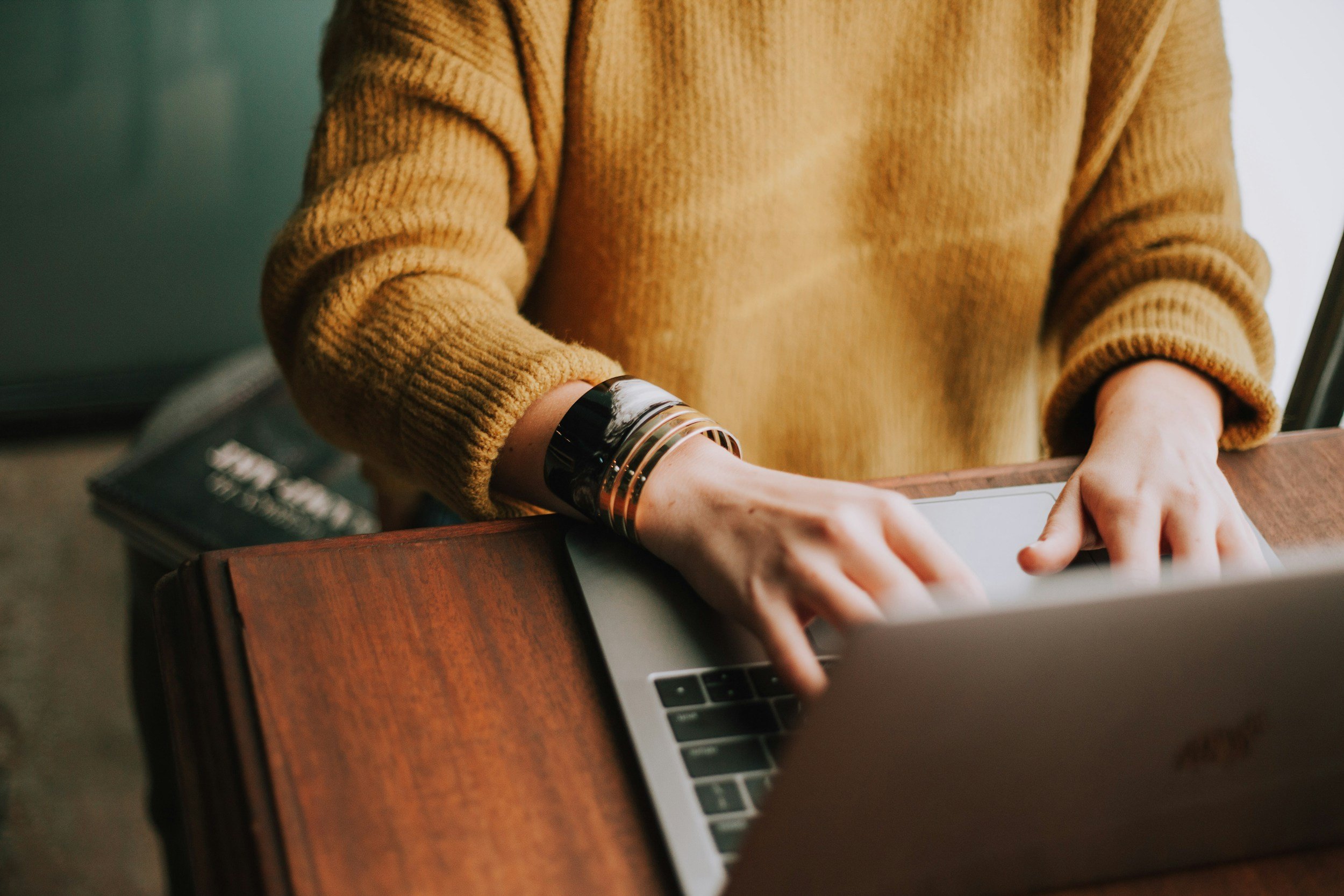 Person typing on a laptop at a wooden desk