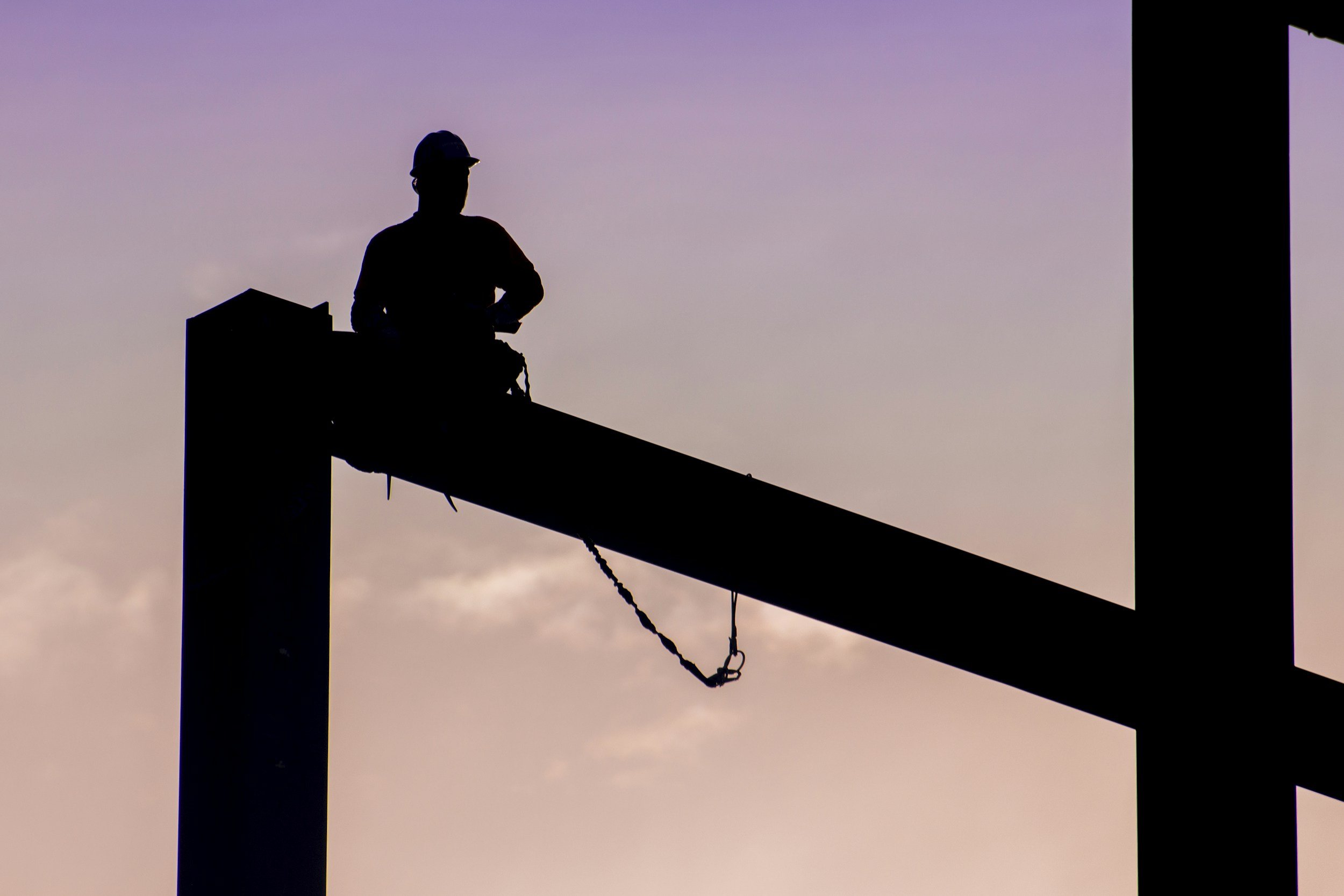 Silhouette of a structural engineer on a steel beam at sunset