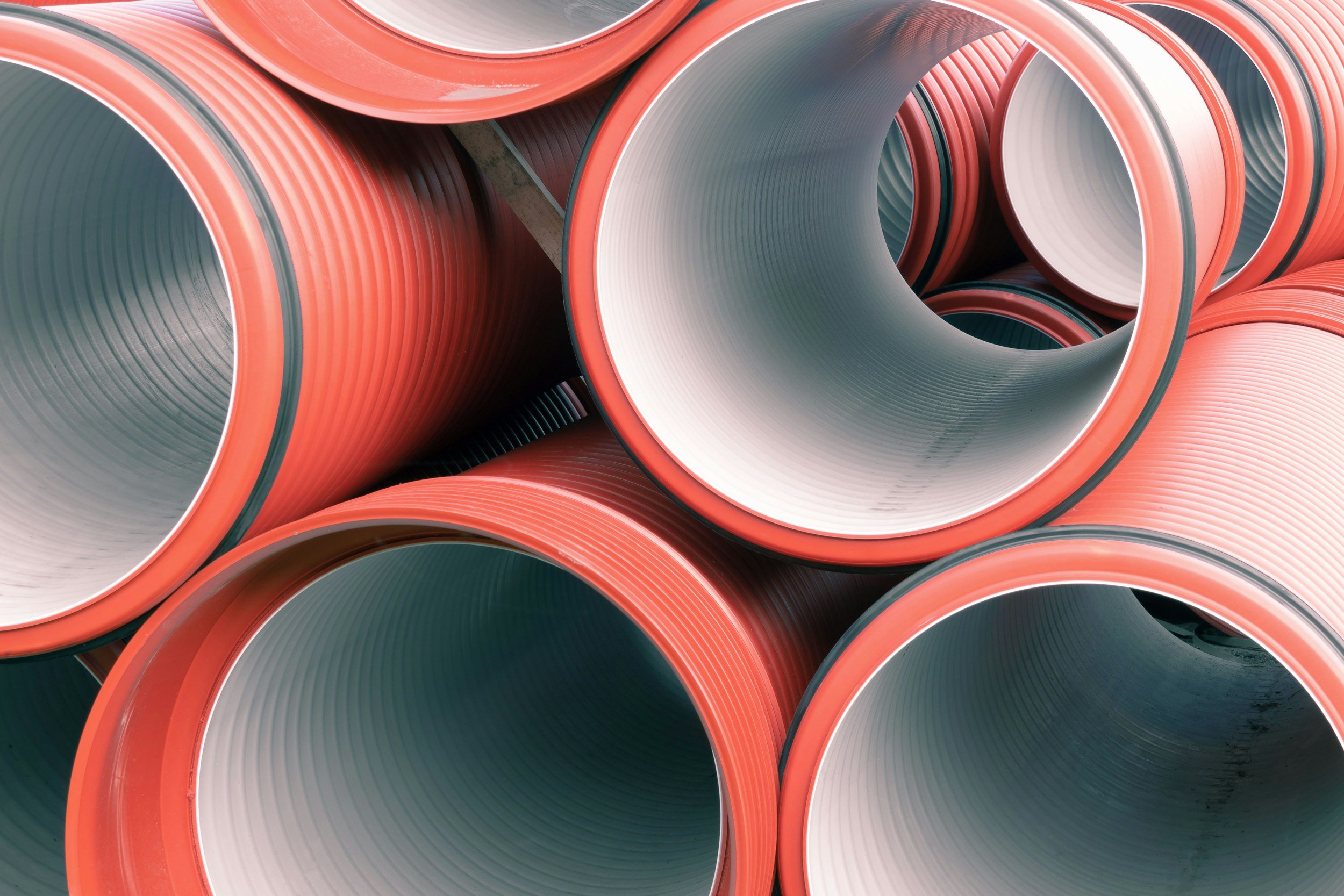 Stacked red corrugated plastic sewage pipes