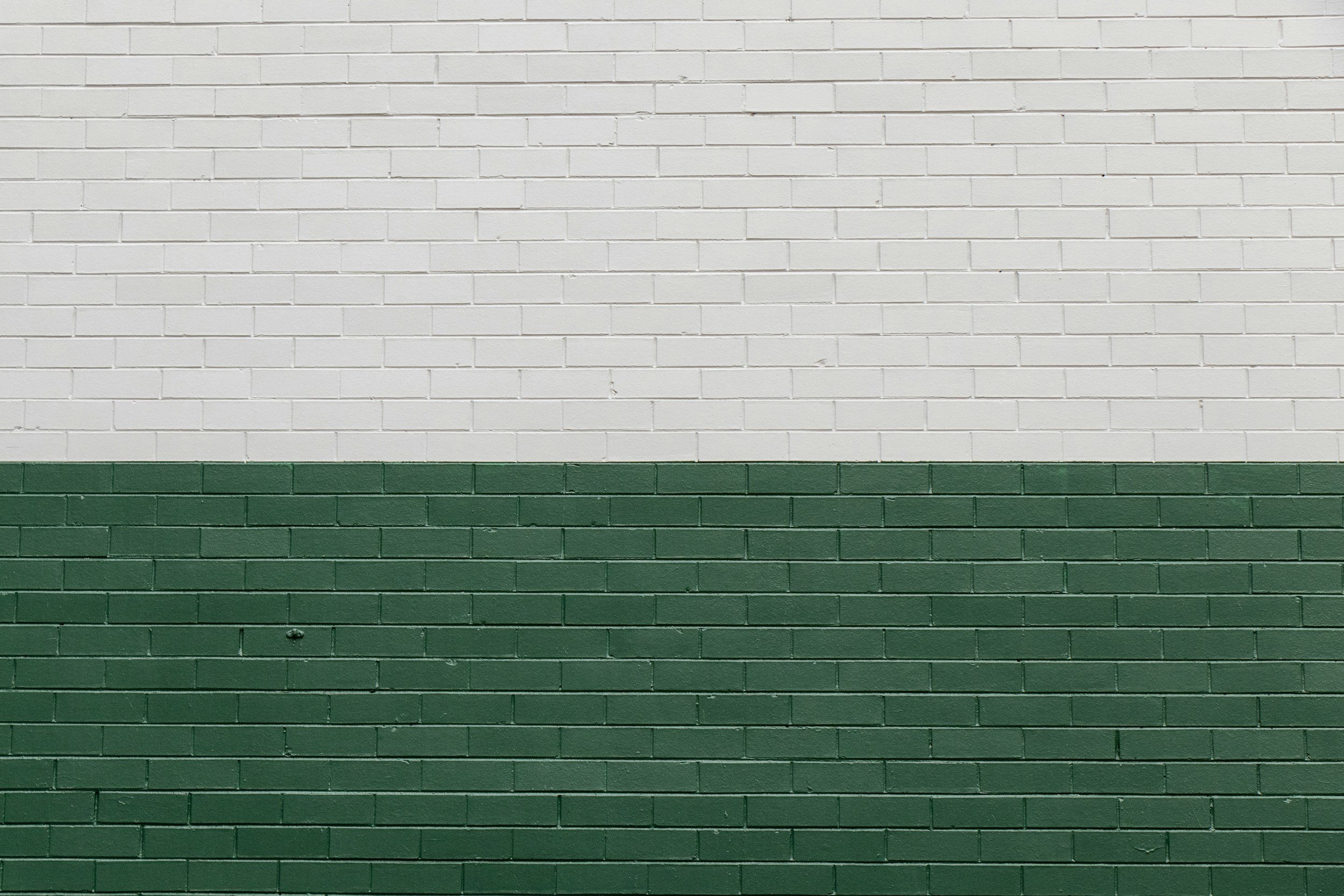 A brick wall painted half white and half green